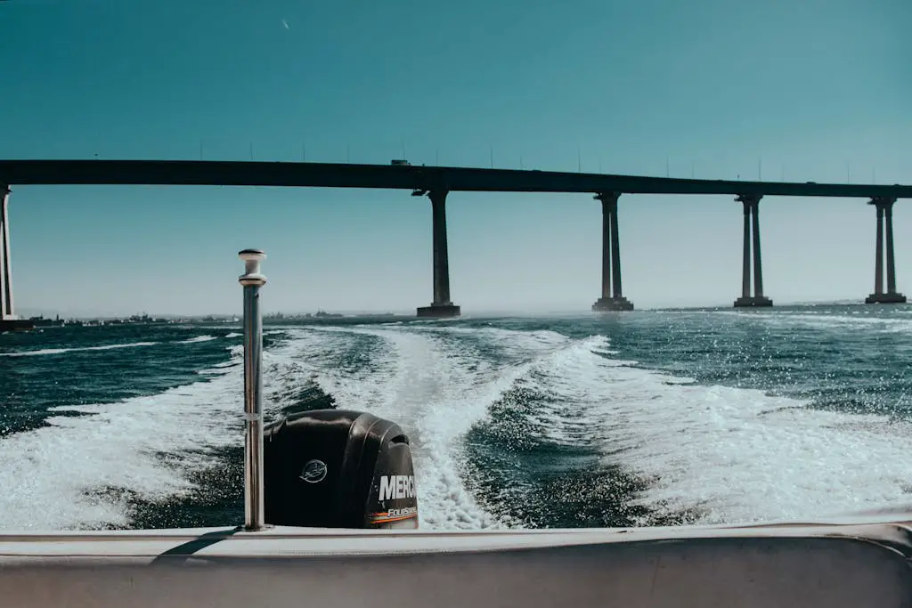 A scenic view from a boat ride underneath a large coastal bridge with a clear blue sky.