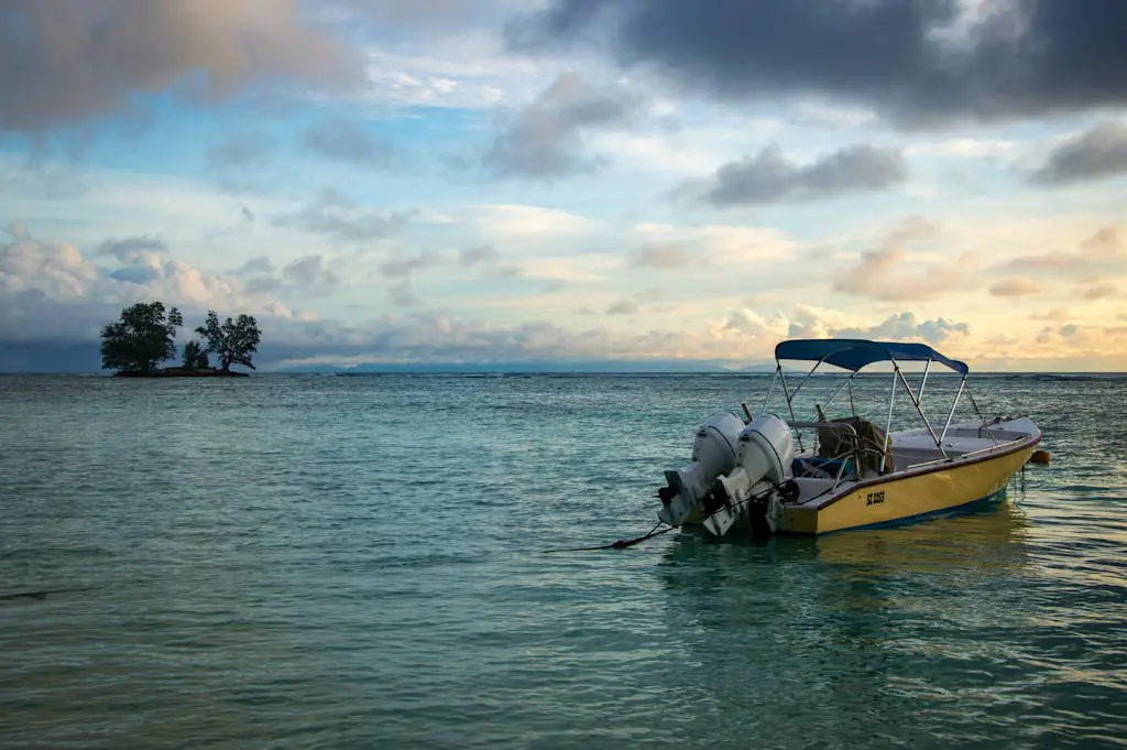 A tranquil seascape with a small boat anchored near an island under a cloudy sky.